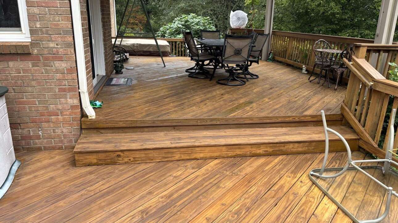 Crew member applying wood finish in suburban home with deck staining near me in Columbia SC