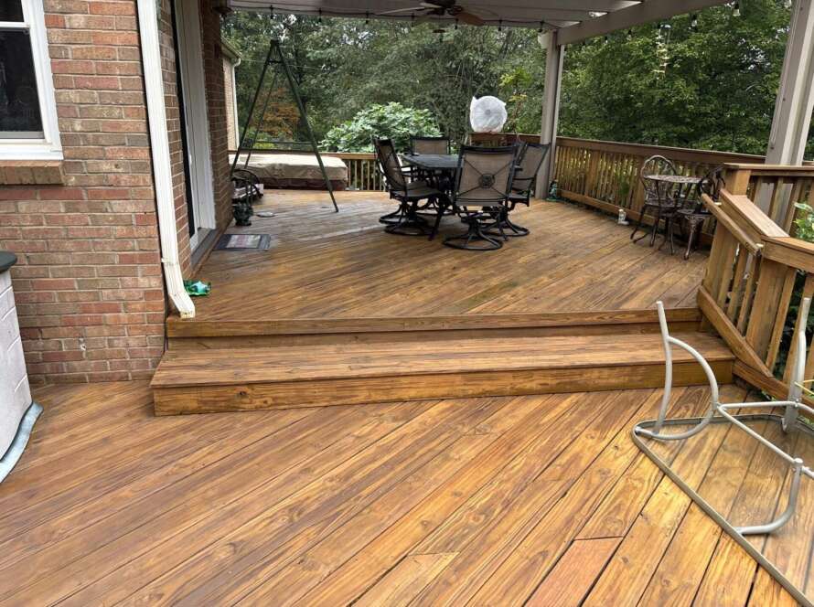Crew member applying wood finish in suburban home with deck staining near me in Columbia SC