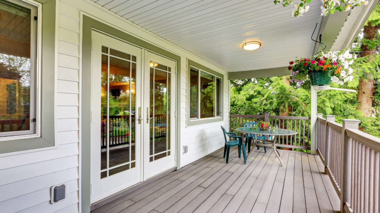Well-maintained home porch with clean siding, neat deck, and hanging plants, reflecting HOA standards for property upkeep and curb appeal.